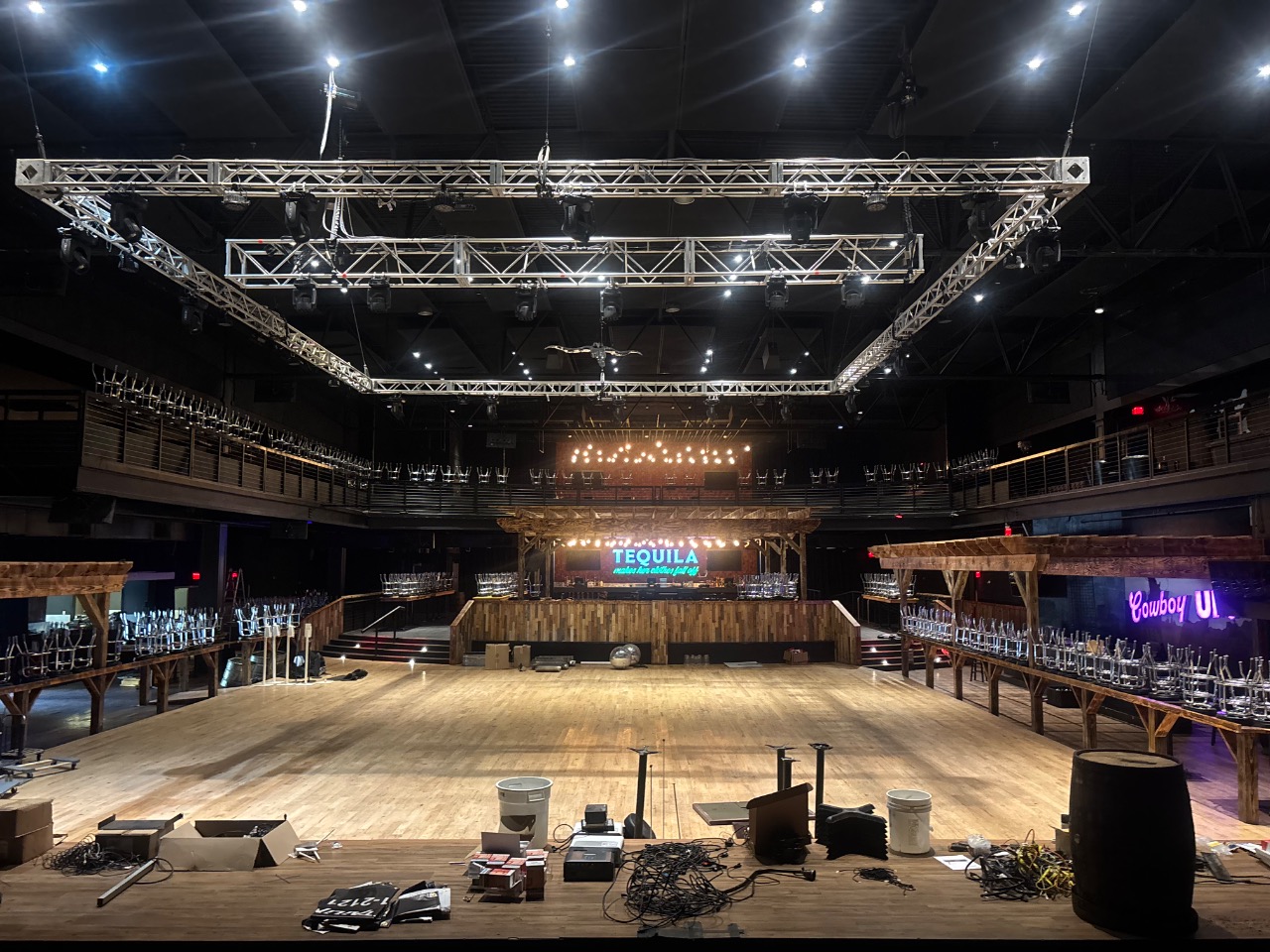 Empty main floor of the event center with the bar, hardwood and overhead truss rig