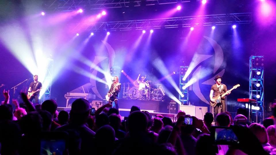 Band performing under purple stage lighting with the crowd in the foreground, Bricktown Event Center.