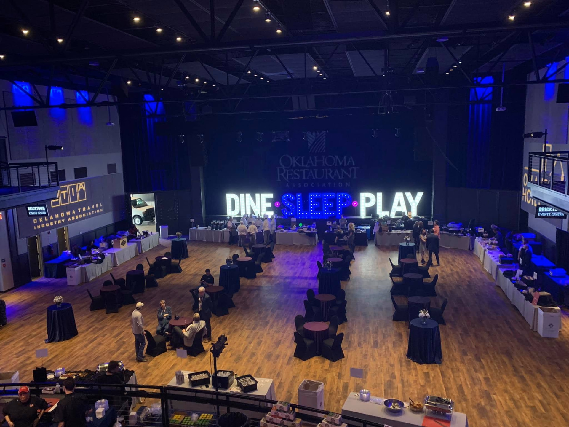 Corporate reception on the venue floor with cocktail tables and marquee signage
